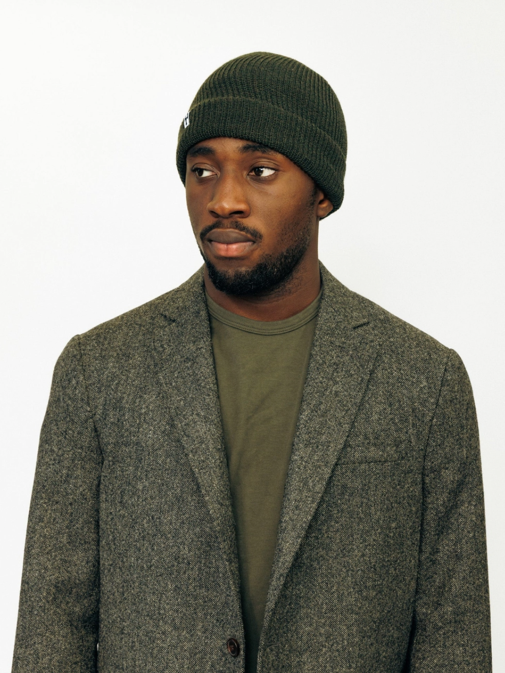 Person wearing American Trench Merino Cardigan Stitch Beanie in Dark olive