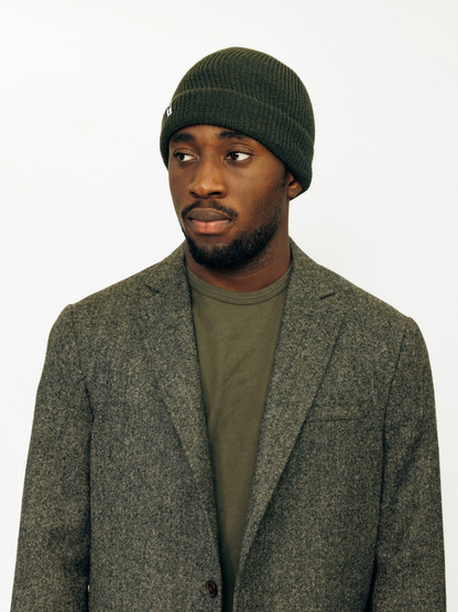 Person wearing American Trench Merino Cardigan Stitch Beanie in Dark olive
