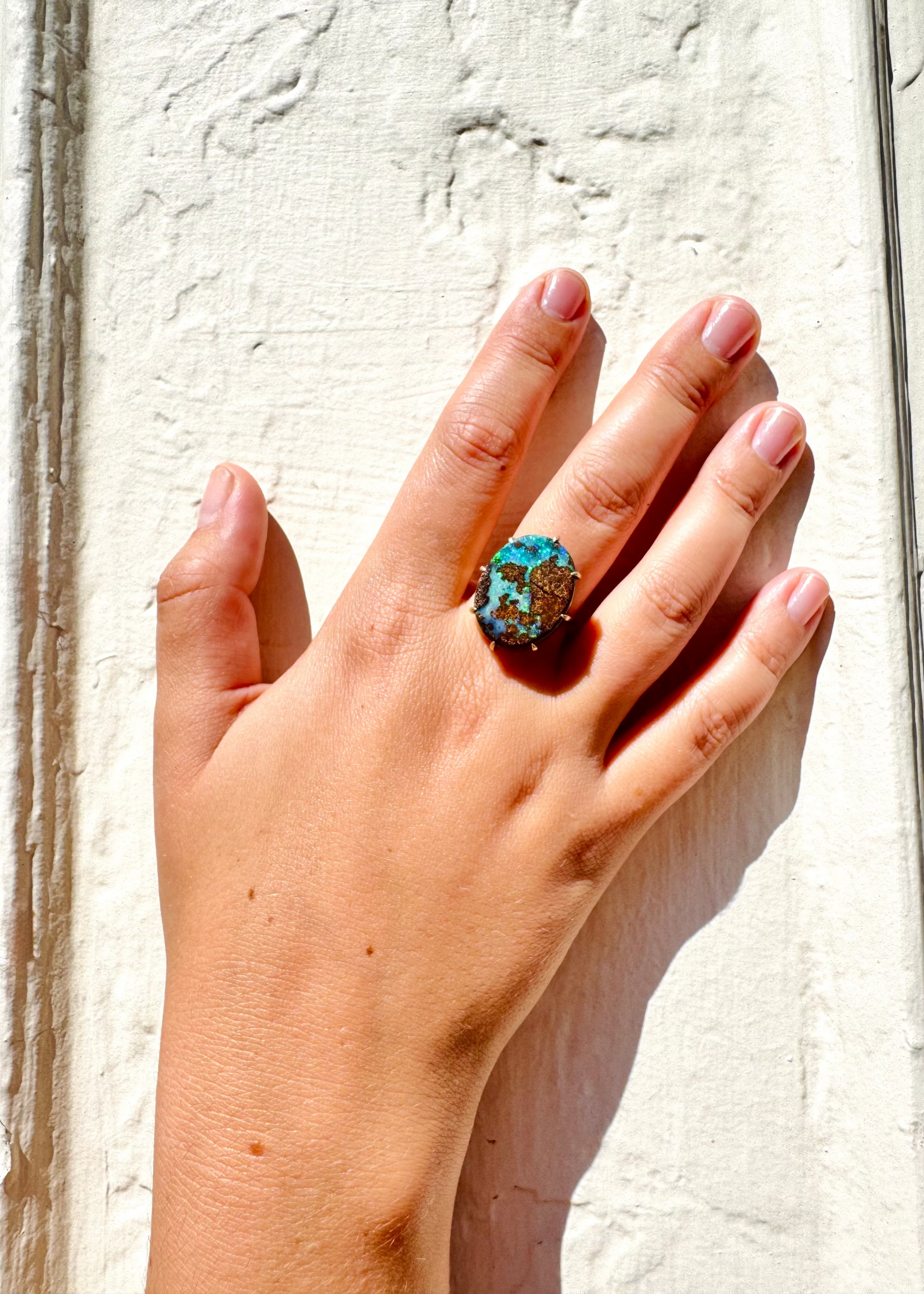 Person wearing Andrea Fohrman fine jewelry 18k yellow gold boulder opal ring