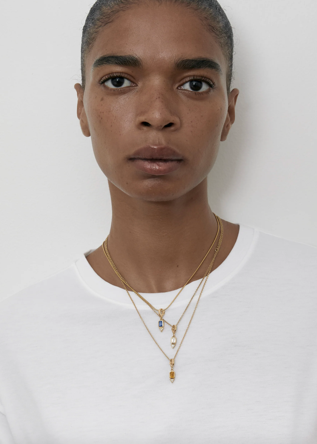 Person wearing Azlee fine jewelry 18k yellow gold Gemstone and Trillion Diamond Charm