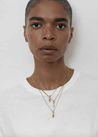 Person wearing Azlee fine jewelry 18k yellow gold Gemstone and Trillion Diamond Charm