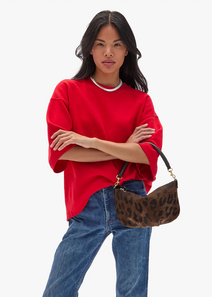 Person carrying Clare V Petit Moyen Messenger in Cocoa Pablo Cat printed Suede bag