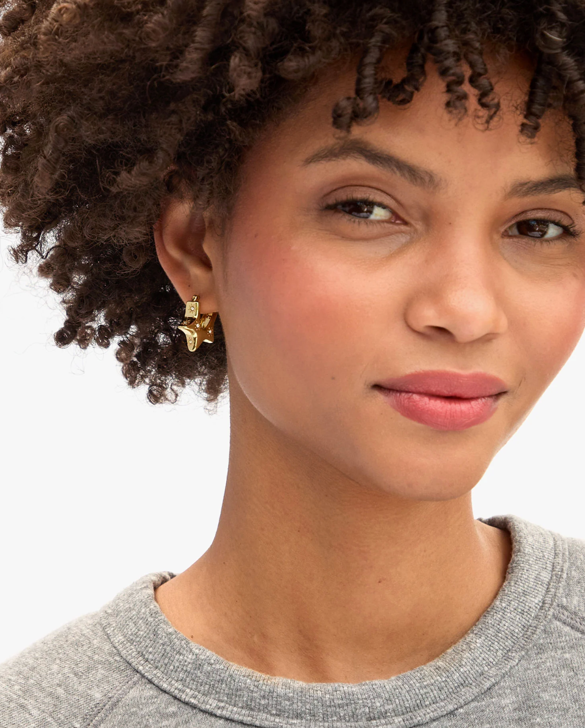 Person wearing Clare V womens gold plated Étoile Hoops earrings