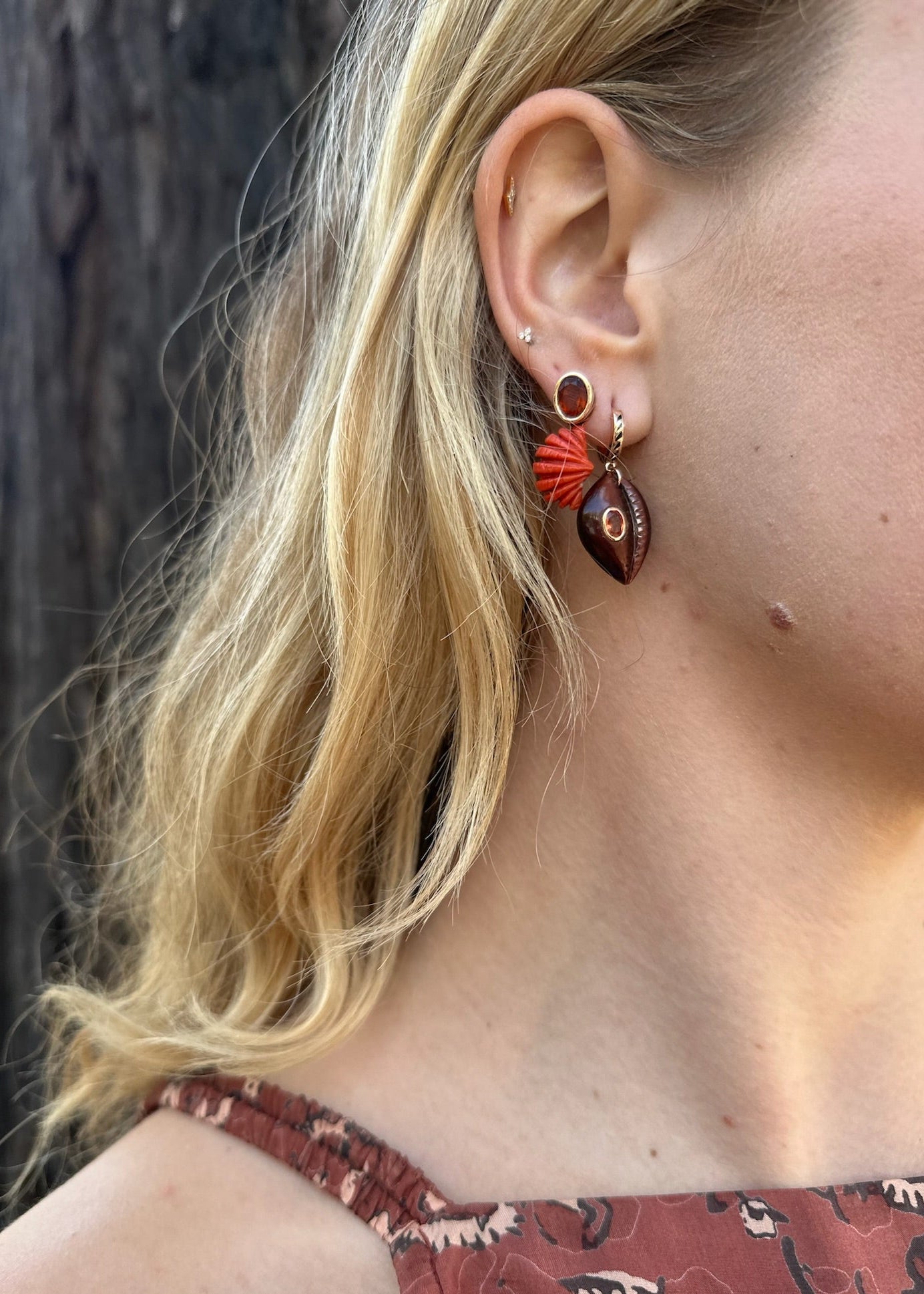 Person wearing Dezso fine jewelry 18k rose gold Red Tigers Eye Cowry Shell Earrings with Sapphires