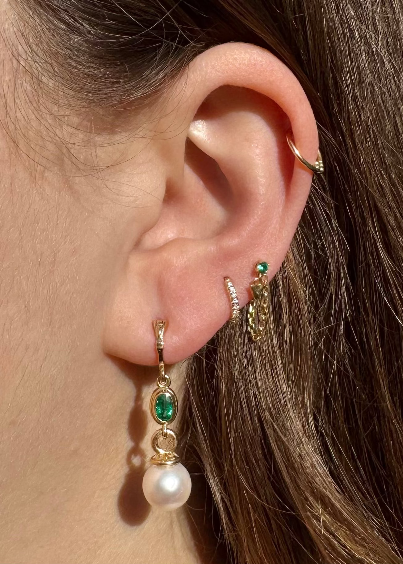 Person wearing Howl fine jewelry 18k yellow gold Emma Pearl and Emerald Earrings