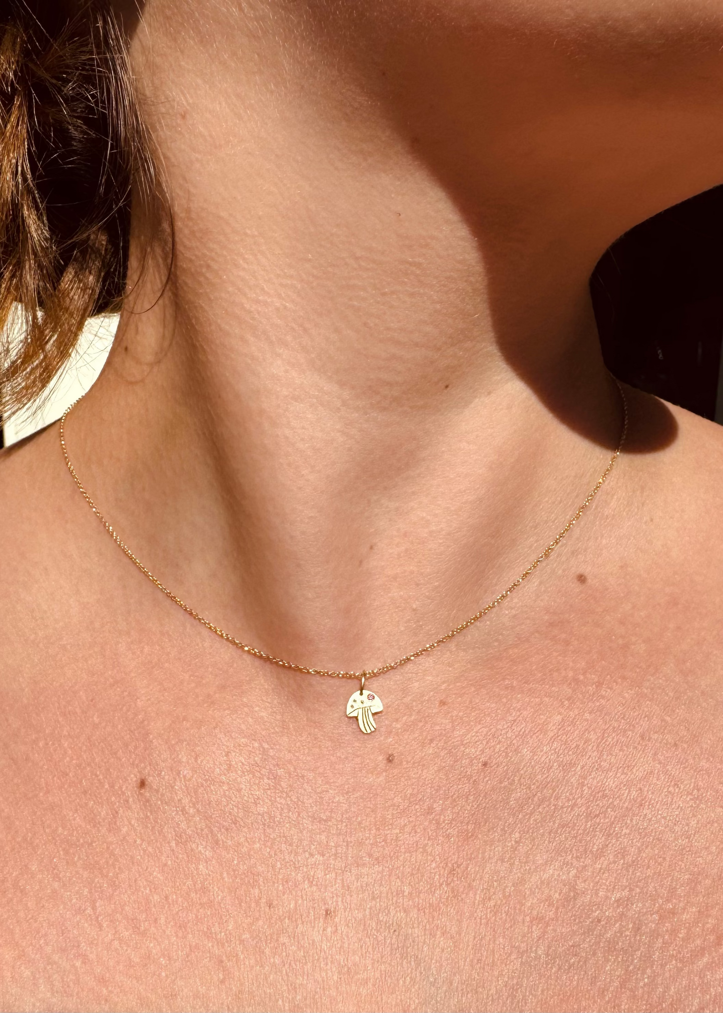 Person wearing Julez Bryant fine jewelry 14k yellow gold pink sapphireTeeny Tiny Mushy Charm Necklace