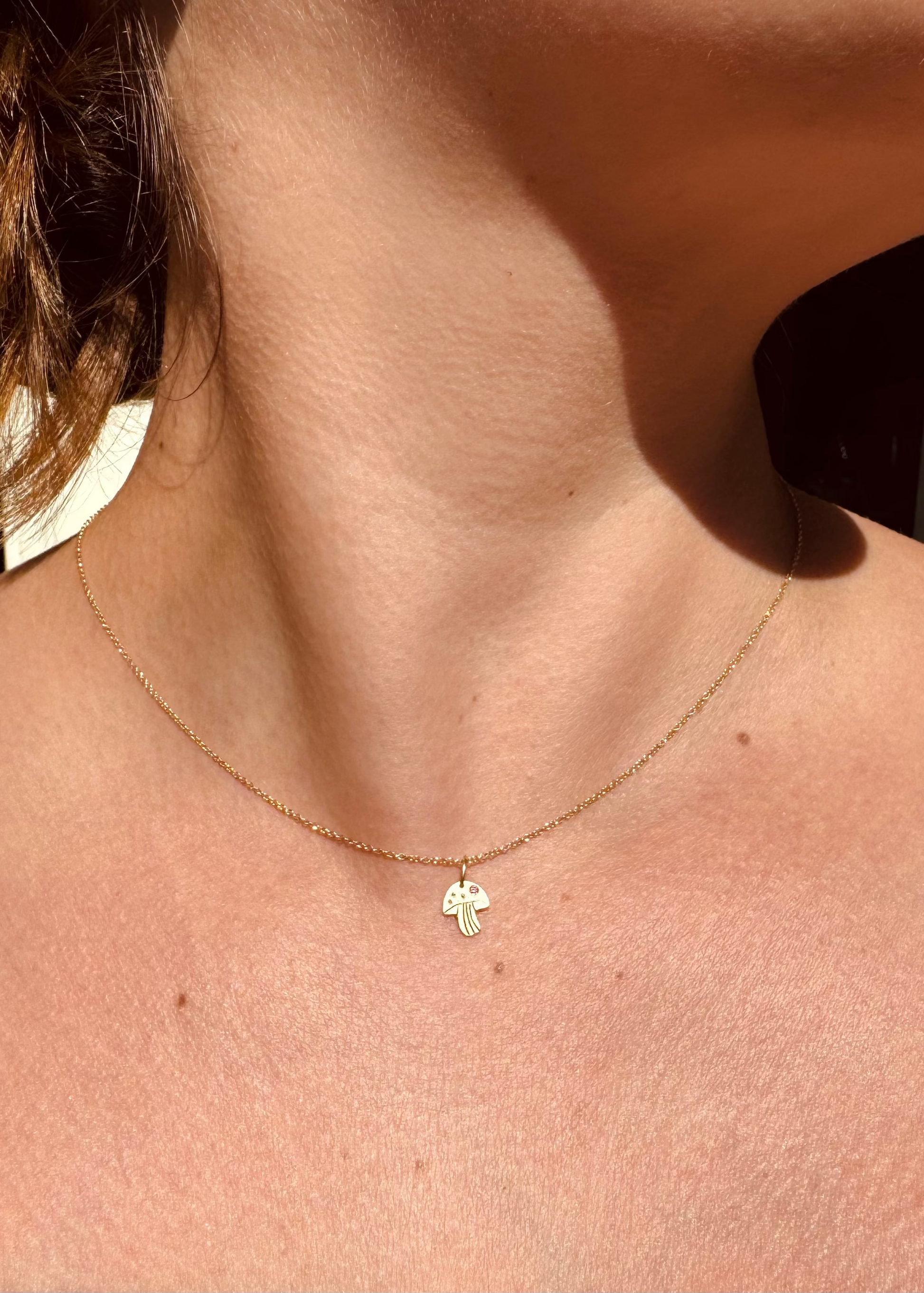 Person wearing Julez Bryant fine jewelry 14k yellow gold pink sapphireTeeny Tiny Mushy Charm Necklace