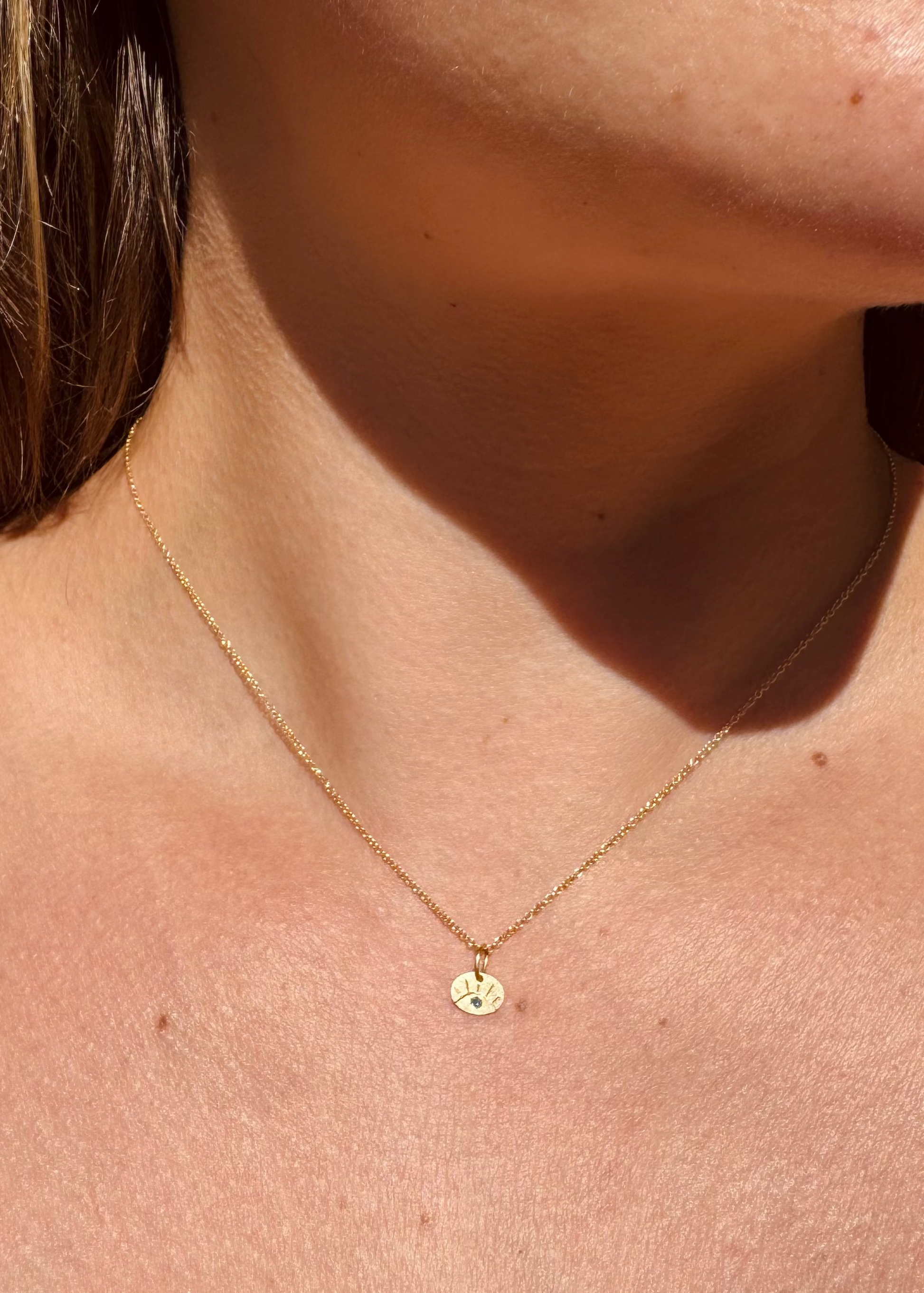 Person wearing Julez Bryant fine jewelry 14k yellow teal diamond Teeny Eye Charm Necklace