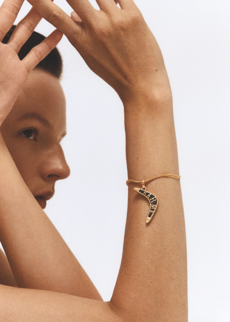 Person wearing Marie Lichtenberg fine jewelry 18k yellow gold Karma Boomerang Pendant with Ebony Charm Bracelet
