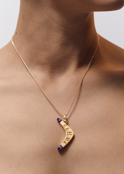 Person wearing Marie Lichtenberg fine jewelry 18k yellow gold Karma Boomerang Pendant Necklace with Lapis 