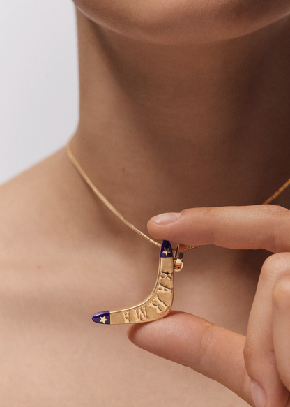 Person wearing Marie Lichtenberg fine jewelry 18k yellow gold Karma Boomerang Pendant with Lapis Necklace