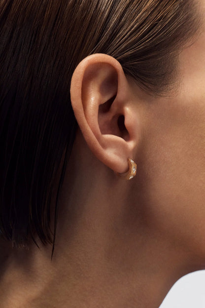 Person wearing Marie Lichtenberg fine jewelry 18k yellow gold ecrou  coco diamond hoop earring