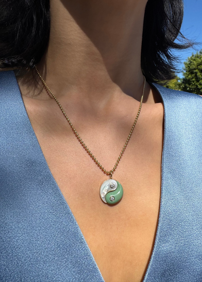 Person wearing Retrouvai 18k yellow gold yin yang charm mother of pearl turquoise diamond necklace