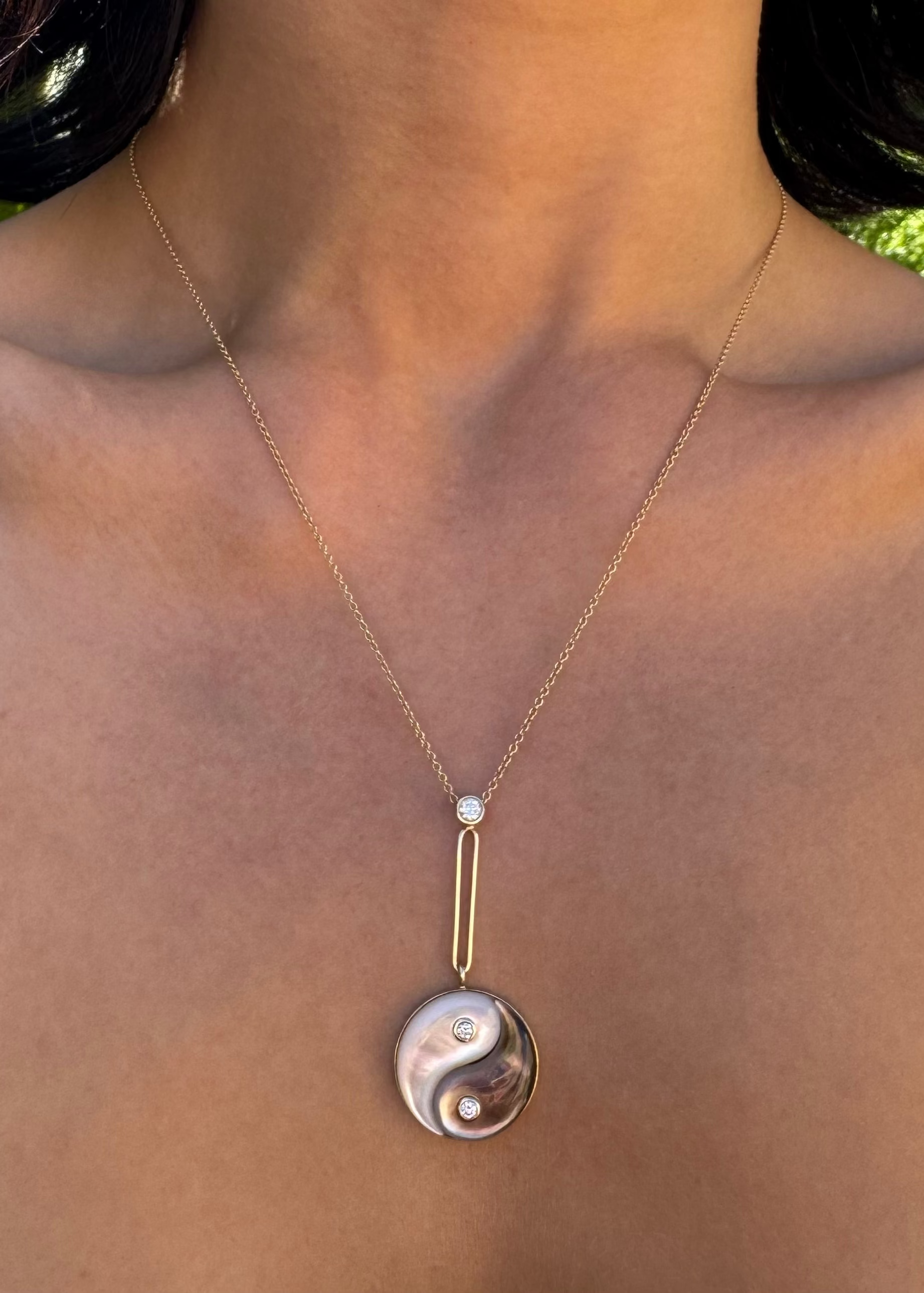 Person wearing Retrouvai fine jewelry 14k gold Double Stone Yin Yang Necklace with Mother of Pearl and Diamonds