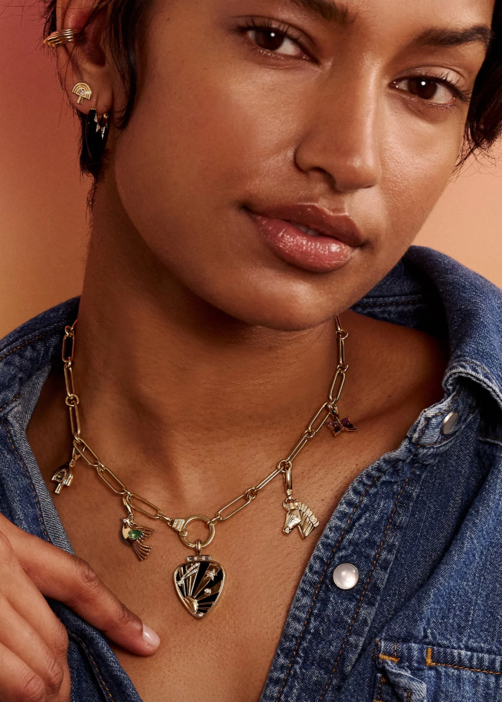 Person wearing Sorellina fine jewelry 18k yellow gold Dove Charm with Emerald necklace