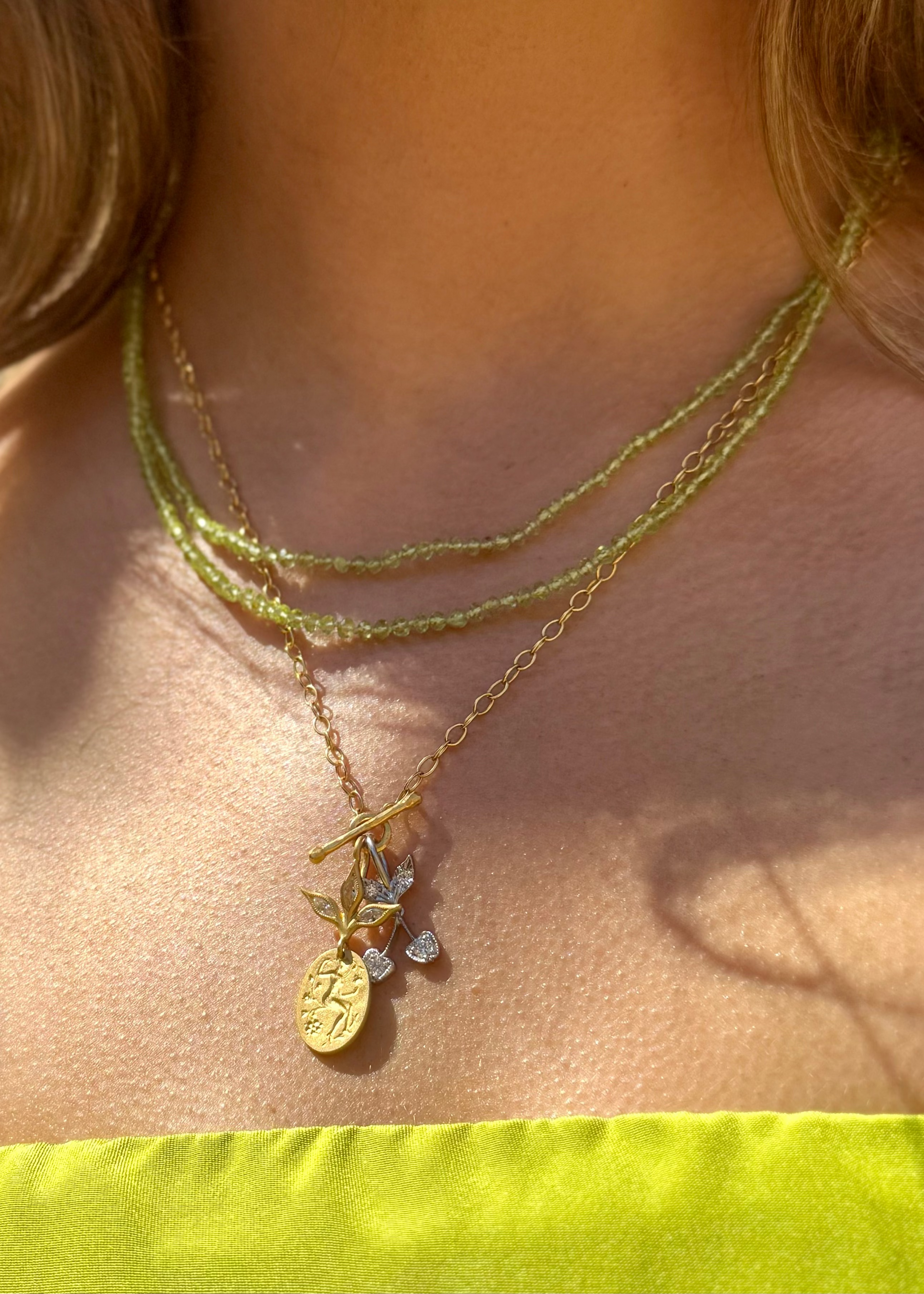person wearing cathy waterman fine jewelry 22k yellow gold Peridot Beaded Necklace tiny lacy chain necklace platinum cherry and goddess pendant