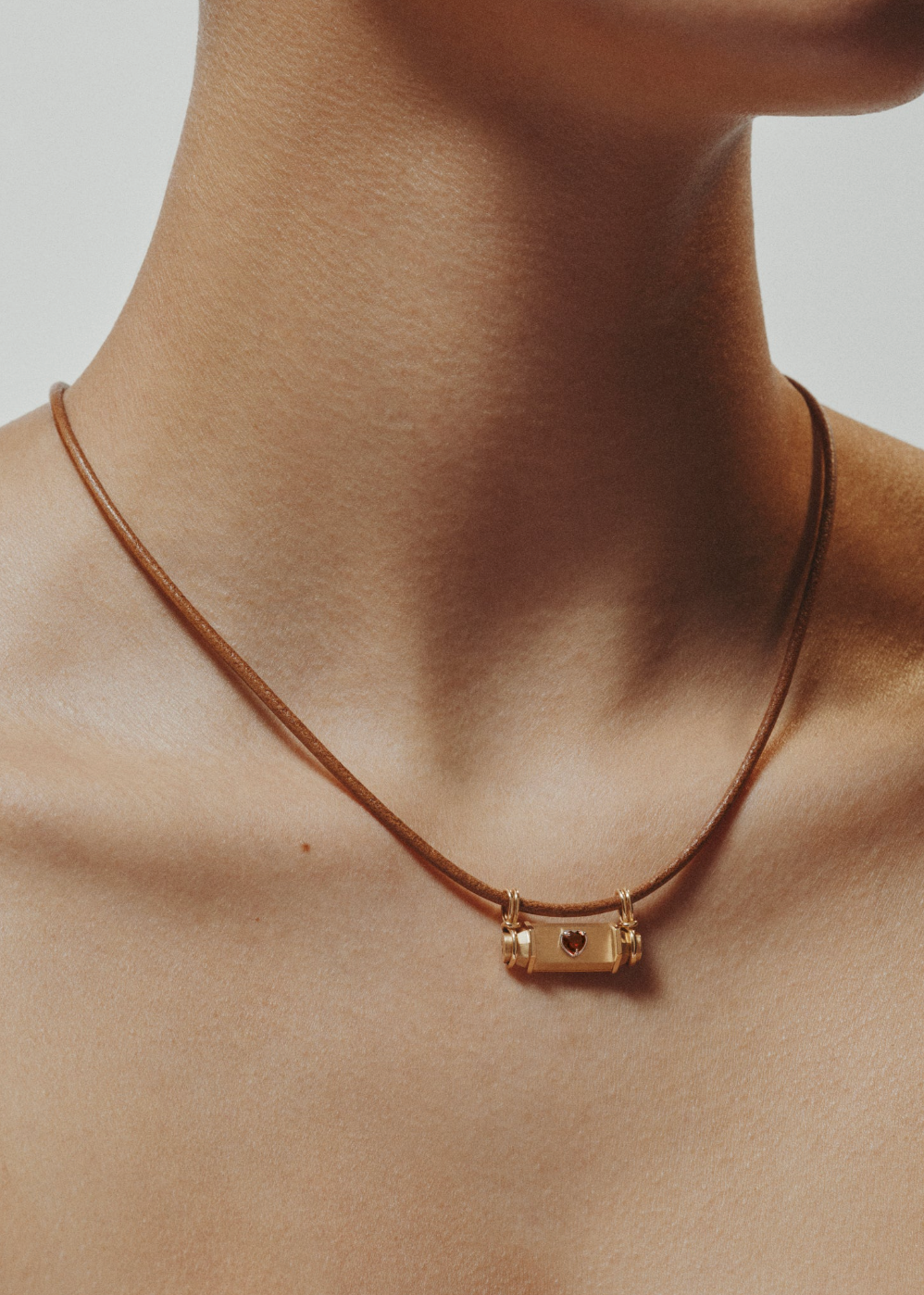person wearing marie lichtenberg fine jewelry 18k yellow gold Heart Smash Locket garnet