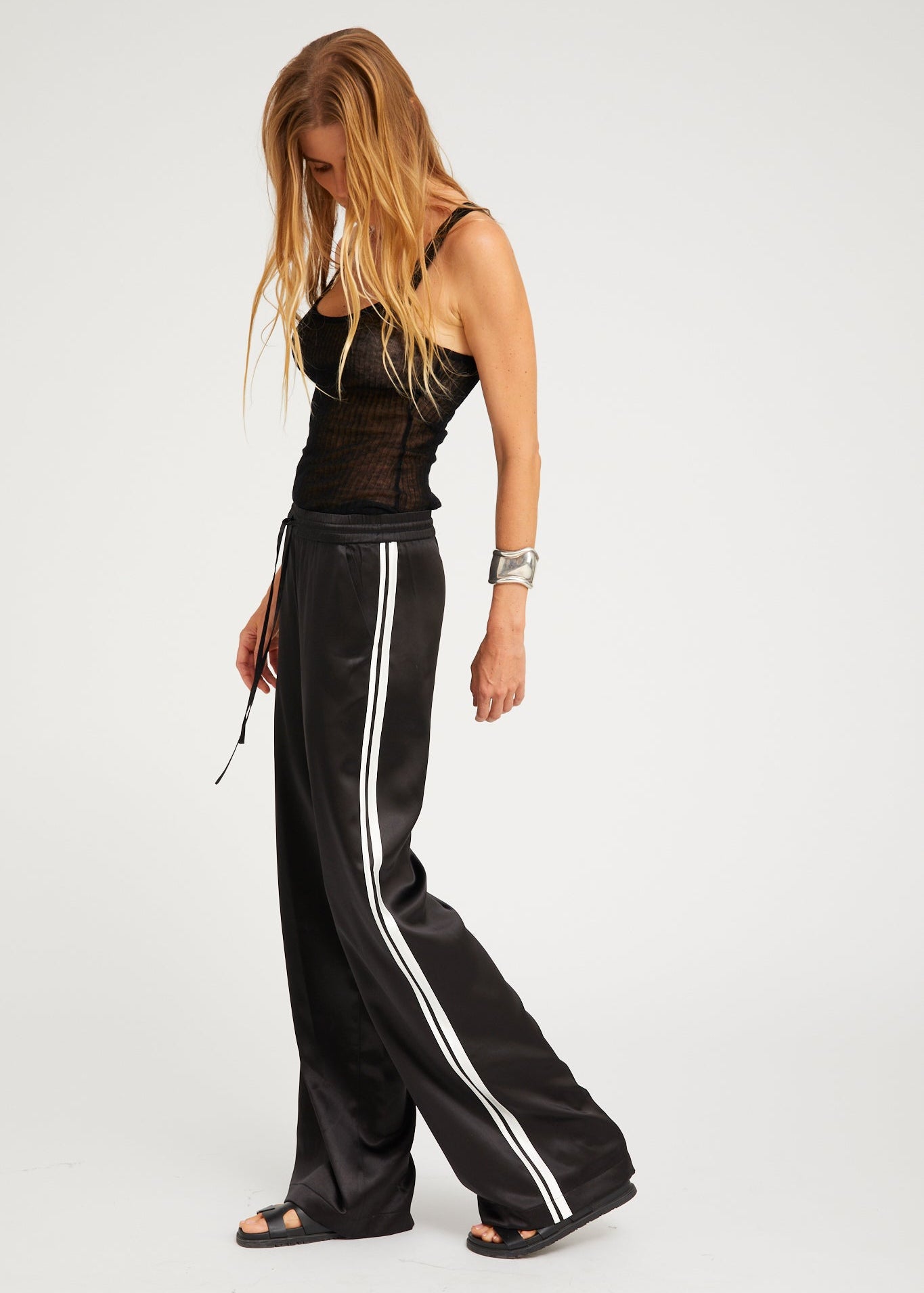 person wearing sprwmn womens Baggy Athletic Silk Pants in Black white stripe